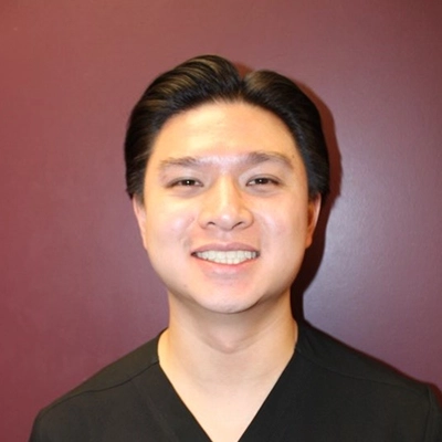 Eric smiling in front of a maroon wall.