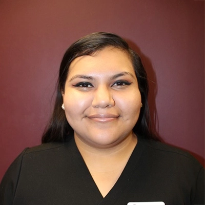 Estefany smiling in front of a maroon wall.